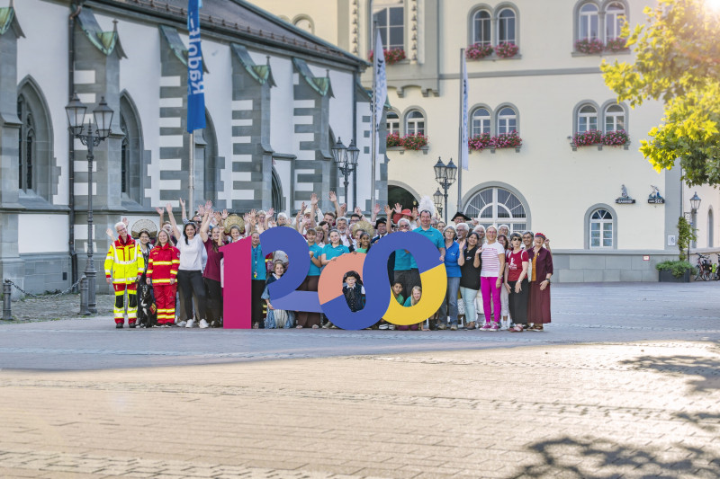 Gruppenfoto vor historischer Architektur mit 1200. Menschen feiern Jubiläum im Freien. Stadtfest-Atmosphäre.