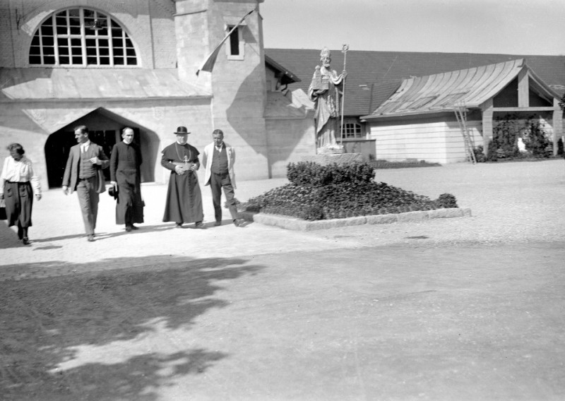Historisches Foto: Priester, Statue vor Kirche. Schwarz-Weiß-Aufnahme, religiöses Gebäude, Männer, Frau.