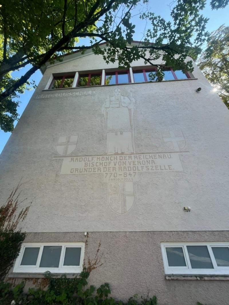 Radolfzeller Schule: Fassade mit Inschrift und Bild von Rudolf, Mönch und Bischof. Architektur in Radolfzell.