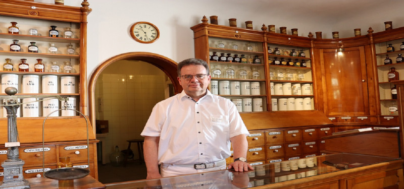 Historische Apotheke: Apotheker vor alten Apothekenschränken mit Arzneiflaschen und Schubladen.