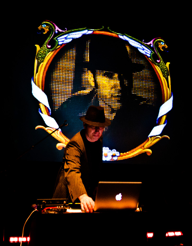 DJ mit Laptop und Hut vor LED-Wand. Musik, Künstler, Performance.