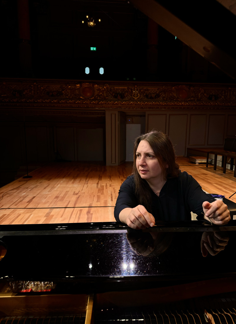 Frau am Klavier auf der Bühne. Pianistin vor Konzert. Musik und Performance.