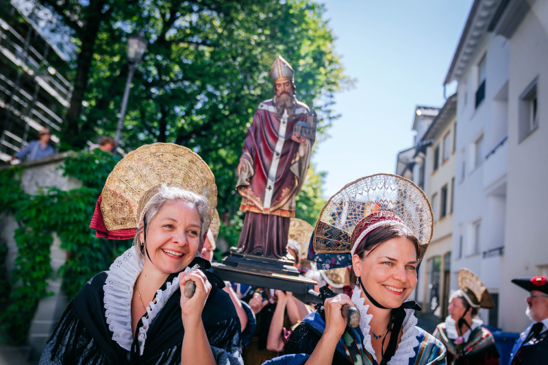 Frauen in Tracht tragen Statue. Traditionelle Kleidung, religiöse Prozession. Brauchtum und Kultur.
