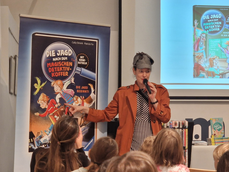 Autorin liest Die Jagd nach dem magischen Detektiv-Koffer vor. Kinderbuchlesung mit Krimi-Rätsel.