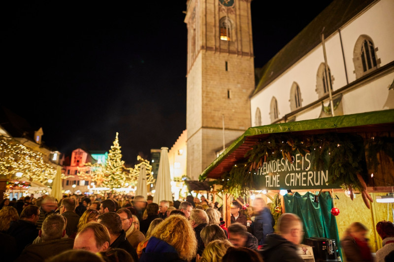 Weihnachtsmarkt Szene: Menschen, Turm, Lichter, Buden. Festliche Stimmung.